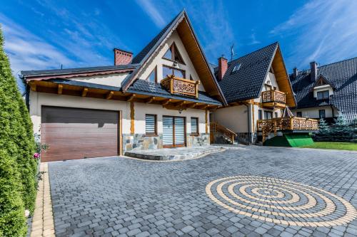 a house with a garage and a driveway at Apartamenty Harenda Ski in Zakopane