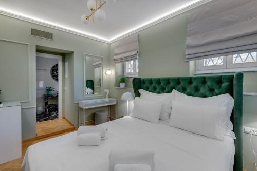 a bedroom with a white bed and a green headboard at Amare Boutique Suites in Ermoupoli
