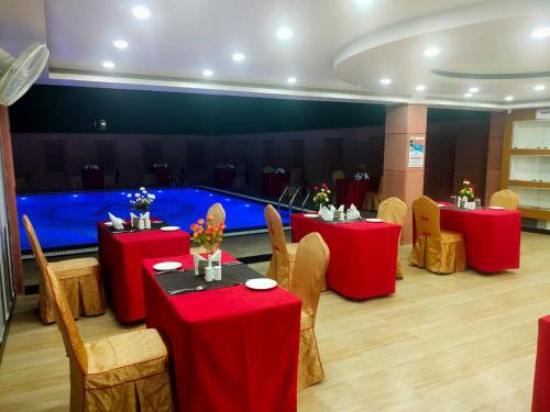 a room with red tables and chairs and a large pool at HOTEL ANAND INTERNATIONAL in Bodh Gaya