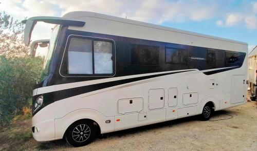 a white and black rv parked in a lot at AGRiCAMPiNG POGGiO Ai PiNi WiNE CAMPiNG in Certaldo