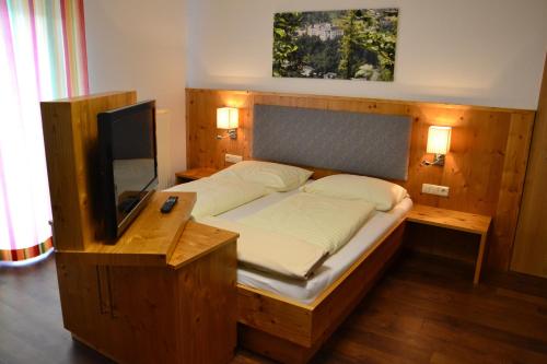 a bedroom with a bed with a wooden frame and a television at Gasthof Käferhube in Murau