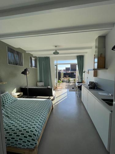a living room with a bed and a kitchen at Het arrangement in Wemeldinge