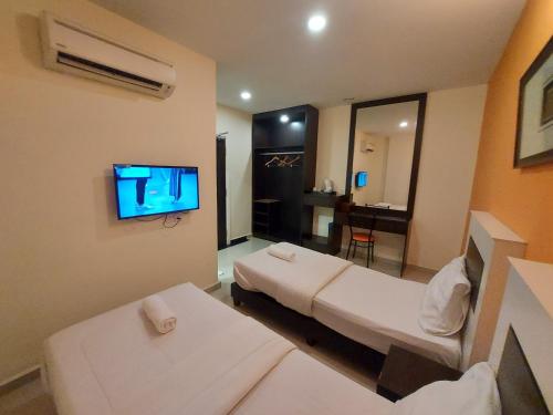 a hotel room with two beds and a flat screen tv at HOTEL SAHARA SDN BHD in Rawang