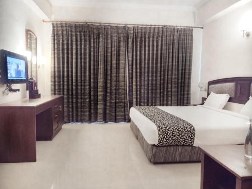 a hotel room with a bed and a television at Hotel Elite Palazzo in Kāladi
