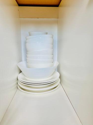 a stack of white plates and bowls in a cabinet at Faizal Madhi Homestay in Kuching