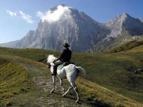 a man riding a horse in front of a mountain at Complesso turistico Aurora - Appartamenti in Poggio Picenze