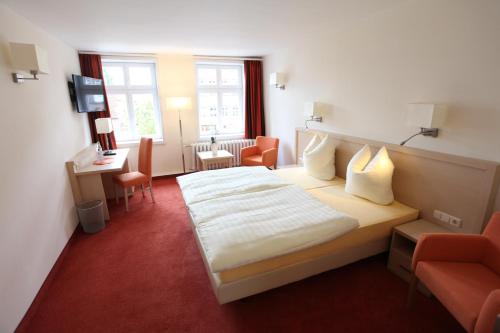 a hotel room with a bed and a desk and chairs at Pension Ratskeller in Hagenow