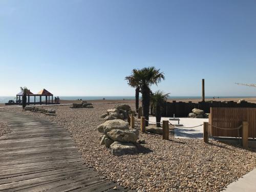 a boardwalk on a beach with trees and rocks at The Leas View in Folkestone