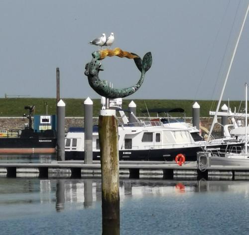 a bird sitting on top of a pole next to a boat at Het arrangement in Wemeldinge