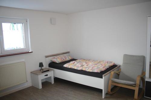 um pequeno quarto com uma cama e uma cadeira em Schönes Zimmer mit Bad für Reisende em Murg
