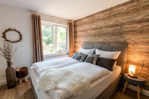a bedroom with a wooden accent wall and a bed at Harzfalke Apartment - Ankommen und wohlfühlen. in Wieda