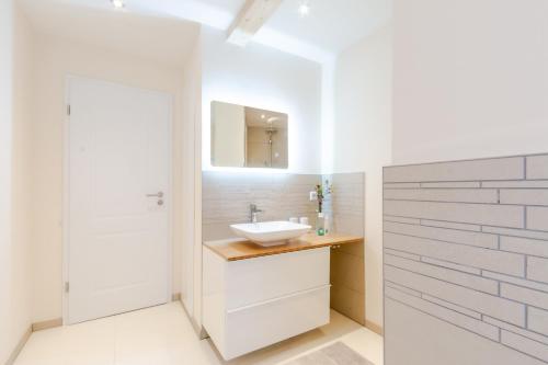 La salle de bains blanche est pourvue d'un lavabo et d'un miroir. dans l'établissement Harzfalke Apartment - Ankommen und wohlfühlen., à Wieda