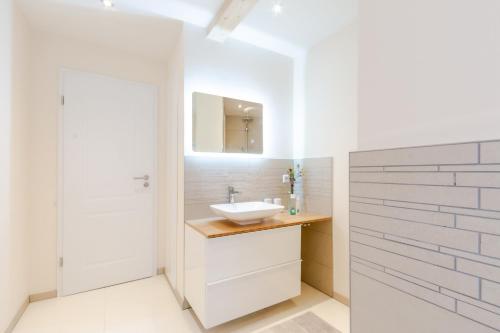 a white bathroom with a sink and a mirror at Harzfalke Apartment - Ankommen und wohlfühlen. in Wieda