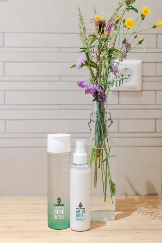 two bottles of sunscreen and a vase with flowers at Harzfalke Apartment - Ankommen und wohlfühlen. in Wieda