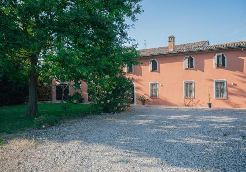una casa naranja con un árbol delante de ella en La Quercia In Giardino, en Ducato di Fabriago
