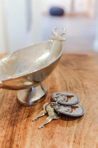 a pair of keys and a metal bowl on a table at Harzfalke Apartment - Ankommen und wohlfühlen. in Wieda