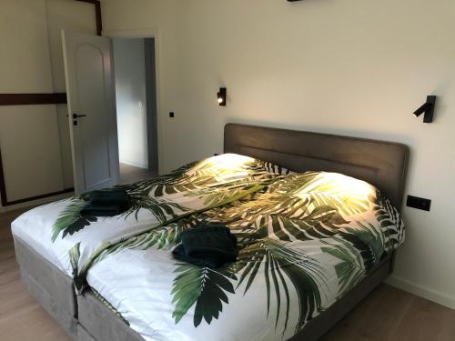 a bedroom with a bed with a bedspread with palm leaves at ROS'a tourist & business appartment in Dendermonde