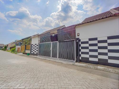 a row of buildings on a street with a fence at OYO 90684 Happy Homestay Syariah in Malang