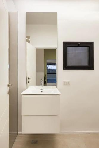 a white bathroom with a sink and a mirror at RENOVATED LARGE 3RM APARTMENT 5 MIN FROM THE BEACH in Tel Aviv