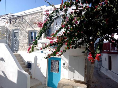 une maison blanche avec une porte bleue et des fleurs dans l'établissement Tristrato, à Parikia