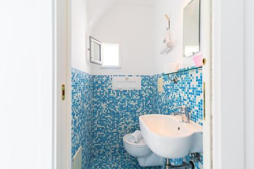 W wyłożonej niebieskimi kafelkami łazience znajduje się umywalka i toaleta. w obiekcie Lopez 20 a Big Family Apartment by Napoliapartments w mieście Neapol