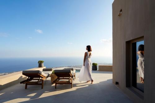 two women walking on a balcony looking out at the ocean at Santorini Sky, The Lodge in Pirgos