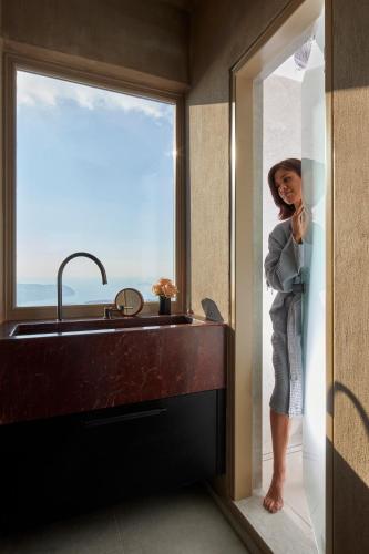 a woman standing in a kitchen with a sink at Santorini Sky, The Lodge in Pirgos