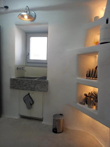 a white bathroom with a sink and a window at Tristrato in Parikia