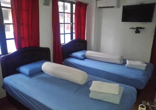 two beds in a room with red curtains at ASH HOTEL in Seremban