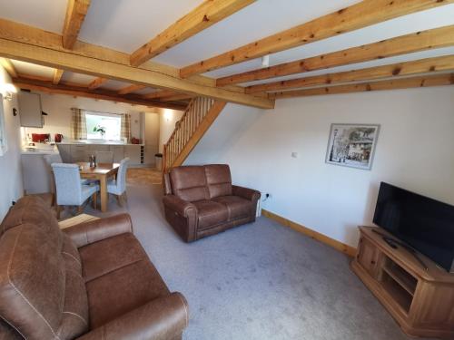 a living room with a couch and a television at The Trotting Mare Holiday Lets - Adults Only in Wrexham