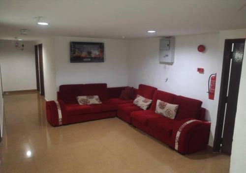 a living room with a red couch in a room at ASH HOTEL in Seremban
