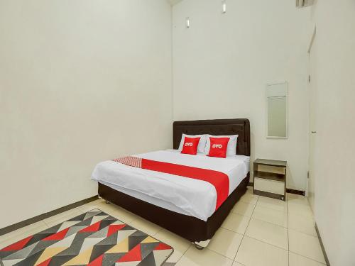 um quarto com uma cama grande e almofadas vermelhas em OYO 90684 Happy Homestay Syariah em Malang