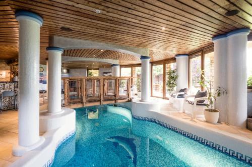 an indoor swimming pool with columns and a wooden ceiling at Private Villa with indoor pool in Budapest