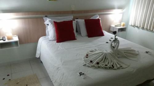 a bedroom with a large white bed with red pillows at Hotel Conde Alemao in Jaguariaíva