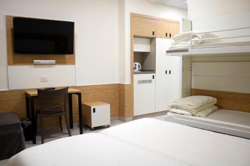 um quarto com uma cama e uma secretária com uma televisão em HI - Pkiin Hostel em Buqei‘a