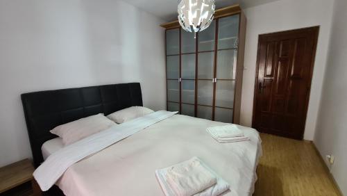 a bedroom with a large bed with white sheets and a chandelier at White Glamour in Buzău