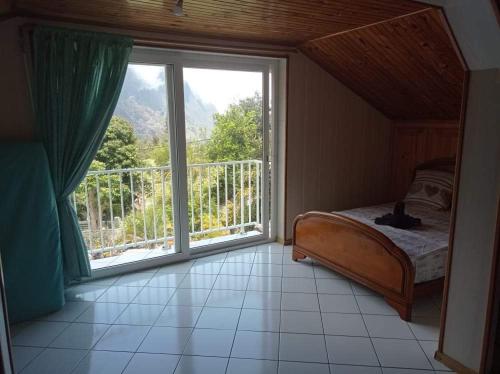 a bedroom with a bed and a large window at La Villa du Sculpteur Palmiste Rouge Cilaos, maison entière in Cilaos