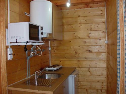 a kitchen with wooden walls and a sink and a microwave at Cabañas El Robledo in El Robledo