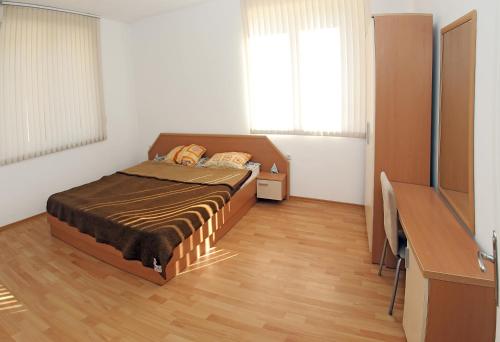 Un dormitorio con una cama y una cómoda y dos ventanas. en Kirovi Apartment, en Primorsko