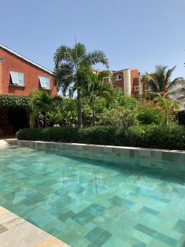 a swimming pool in front of a building with palm trees at Villa Aquarêve in Saly Portudal