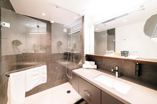 a bathroom with a sink and a shower and a mirror at Park Hotel Winterthur in Winterthur