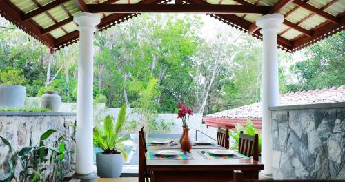 Un porche con una mesa con platos y flores. en Terrace Garden Ayurveda Resort, en Weligama