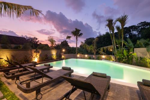 a swimming pool with chaise lounge chairs and a resort at Musa Canggu in Canggu