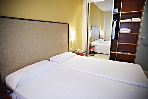 a bedroom with a large white bed in a room at Apartamentos Vértice Sevilla Aljarafe in Bormujos