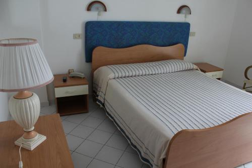 Schlafzimmer mit einem Bett mit blauem Kopfteil und einer Lampe in der Unterkunft Hotel Mareblu in Amantea