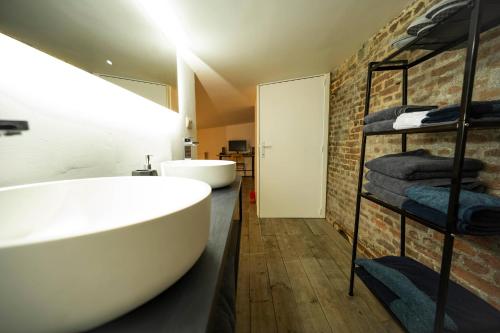 uma casa de banho com uma grande banheira branca e uma parede de tijolos em L'atelier de Liège: Tranquillité & Effervescence em Liège