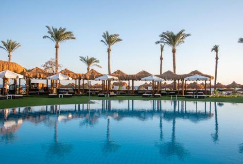 a large swimming pool with umbrellas and palm trees at Sunrise Remal Beach Resort in Sharm El Sheikh