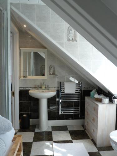 a bathroom with a sink and a mirror and a staircase at Failte Bed & Breakfast in Oban