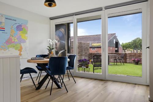 Vakantiehuis Bij Vermeer في Een: غرفة طعام مع أبواب زجاجية منزلقة وطاولة وكراسي