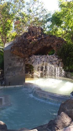 a swimming pool with a waterfall and a stone wall at La casa de Tea in Santa Lucía